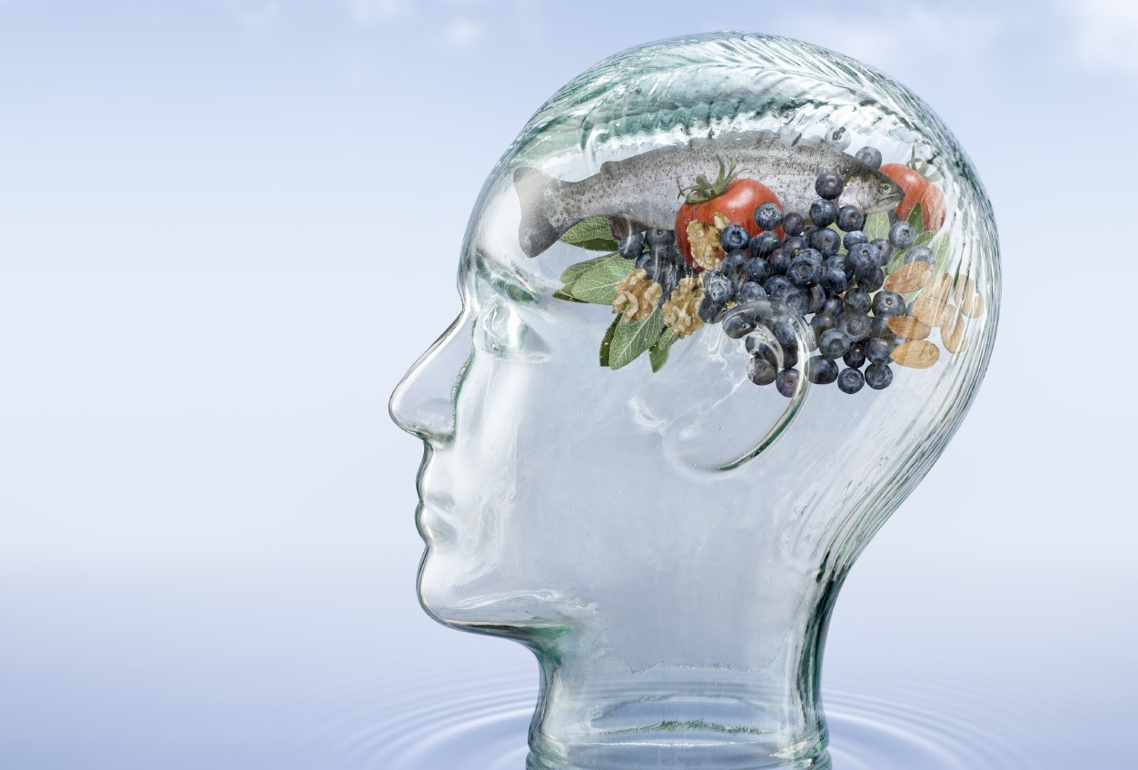 Photo of a glass head on a blue background. The head's "brain" is made up of different foods.